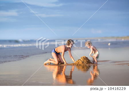 Little funny baby girl and her brother playing together on a bea 10416229