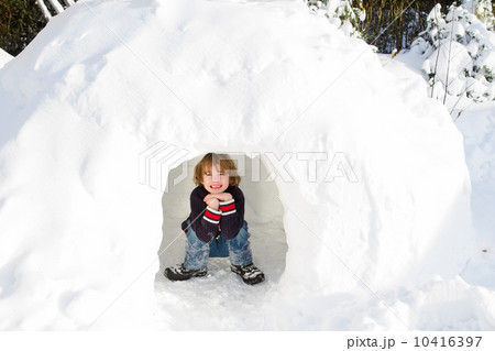 Funny boy playing in a snow igloo on a sunny winter day 10416397
