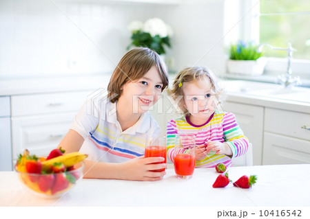 Happy teenager boy and his cute toddler sister having fruit for 10416542