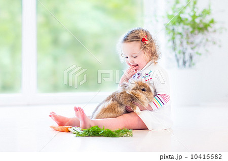 Adorable toddler girl with beautiful curly hair wearing a white 10416682