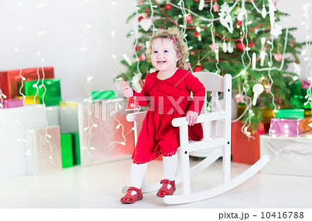 Funny curly toddler girl playing with a red bell in a white rock 10416788
