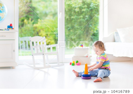 Cute toddler girl playing with a pyramid toy in a white room wit Cute toddler girl playing with a pyramid toy in a white room wit 10416789