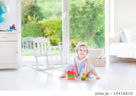 Adorable toddler girl with curly hair wearing a blue dress playi Adorable toddler girl with curly hair wearing a blue dress playi 10416819