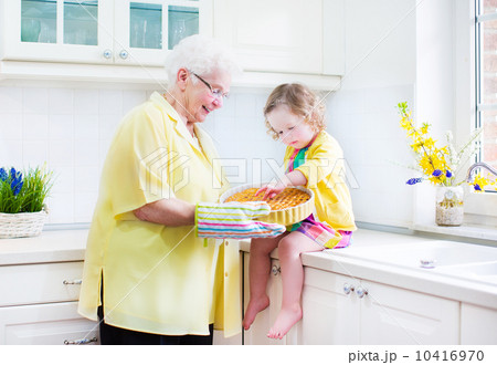 Happy grandmother and little girl baking a pie in a white kitche Happy grandmother and little girl baking a pie in a white kitche 10416970