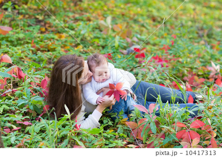 Young beautiful mother and her baby daughter lying among red lea 10417313