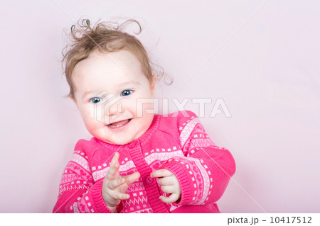 Cute baby girl in a pink knitted sweater with hearts pattern on a pink blanket 10417512