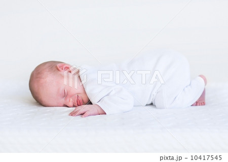 Little newborn baby sleeping on a white knitted blanket 10417545