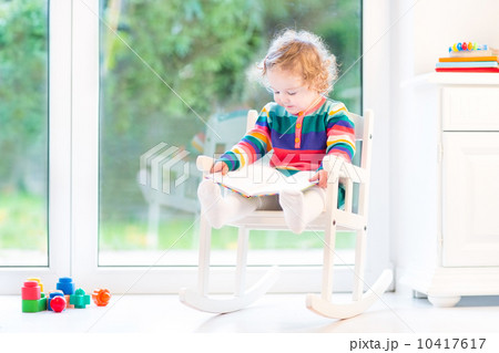 Adorable toddler girl with curly hair wearing a colorful knitted 10417617
