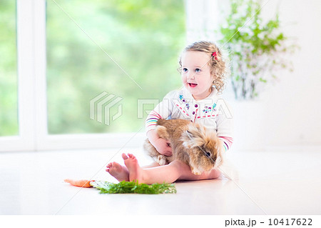 Adorable toddler girl with beautiful curly hair wearing a white 10417622