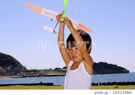 海岸で模型飛行機を飛ばす子供 10423966