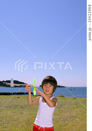 海岸で模型飛行機を飛ばす子供 10423968