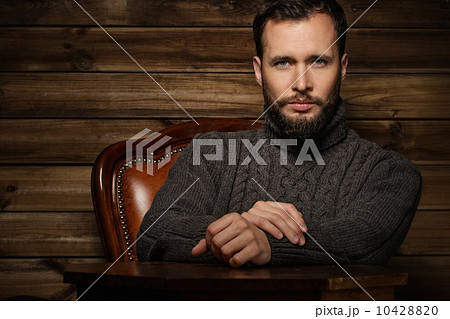 Handsome man wearing cardigan in wooden rural house interior 10428820