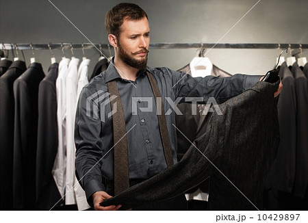 Handsome man with beard choosing jacket in a shop Handsome man with beard choosing jacket in a shop 10429897