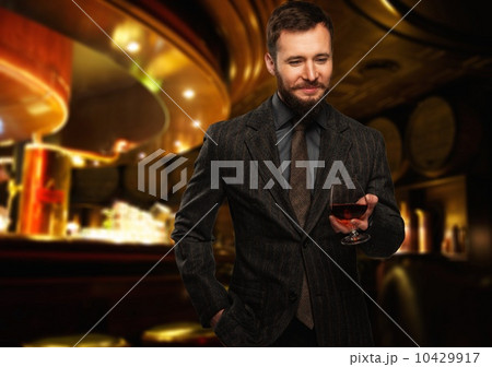 Handsome well-dressed man in jacket with glass of beverage in restaurant interior Handsome well-dressed man in jacket with glass of beverage in restaurant interior 10429917