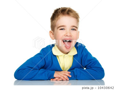 Sly little boy in blue cardigan and yellow shirt showing tongue 10430642