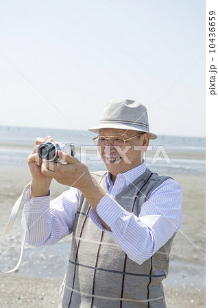 海辺で写真を撮るシニア男性 10436659
