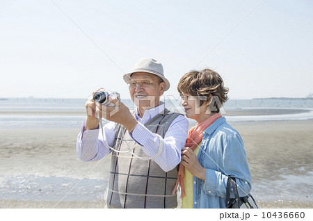 海辺で写真を撮るシニア夫婦 10436660
