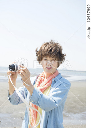 海辺で写真を撮るシニア女性 10437990