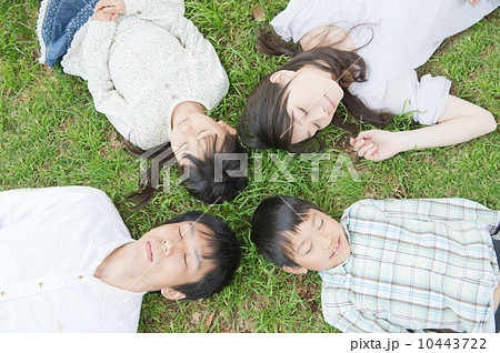 芝生に寝転ぶ4人家族の写真素材
