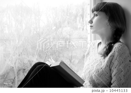 Young adult girl reading book near the window. Black and White image Young adult girl reading book near the window. Black and White image 10445133