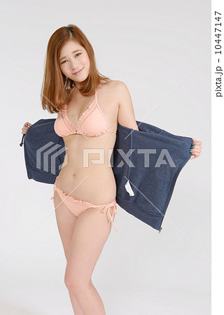 パーカーを脱ぐ水着姿の若い女性の写真素材
