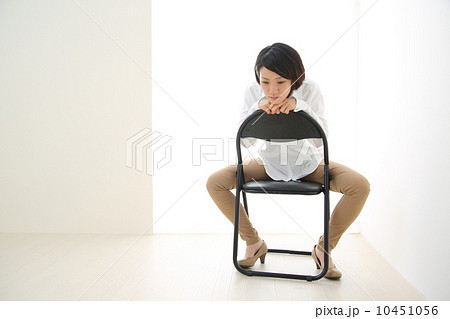 パイプ椅子に股がる女性の写真素材