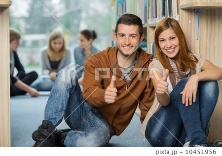 Happy students showing thumb up in library Happy students showing thumb up in library 10451956