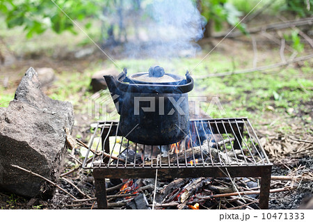 black old smoked teapot on the campfire on picnic in wood in the 10471333