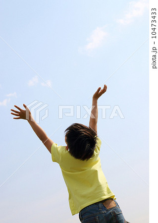 男の子 空に向かって両手を広げるの写真素材