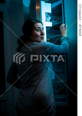 Shot at night of woman opening refrigerator 10490122