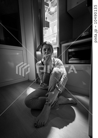 photo of woman sitting next to fridge at night 10490135