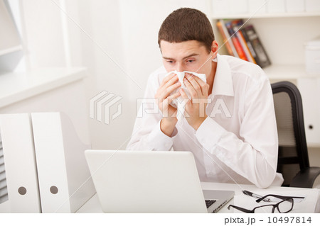man sneezing while working man sneezing while working 10497814