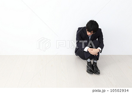 膝を抱えて座る男性社員の写真素材