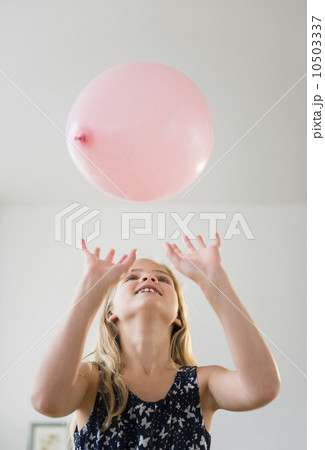 Girl (8-9) playing with pink balloon 10503337