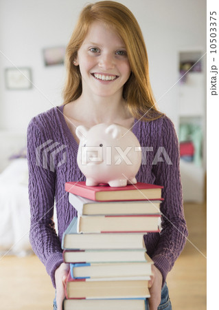 Portrait of girl (12-13) with books and piggy bank 10503375