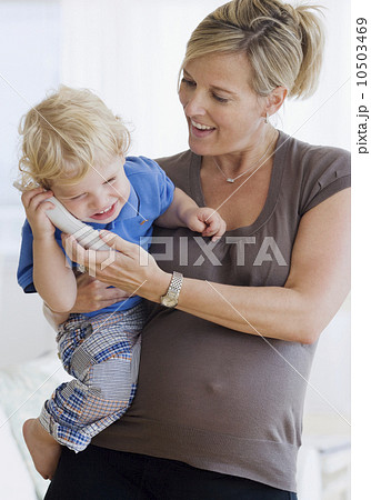 Pregnant mother holding child on telephone Pregnant mother holding child on telephone 10503469