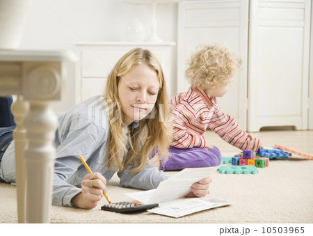 Mother working on calculator while child plays 10503965