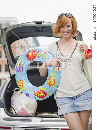 Portrait of young woman with beach gear in front of car 10504089