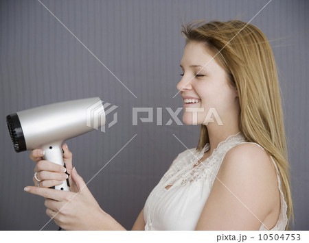 Teenage girl pointing hair dryer at face 10504753