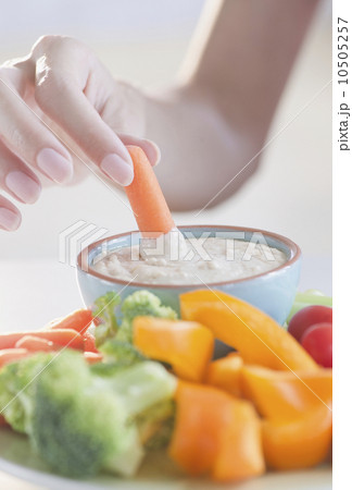 USA, New Jersey, Jersey City, Close-up view of woman hand putting baby carrot into dip 10505257