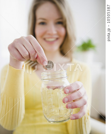 Woman putting coins in a jar 10505387