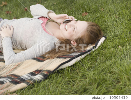 Woman laying in grass talking on cell phone 10505439
