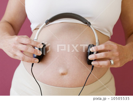 Pregnant woman holding headphones on belly 10505535