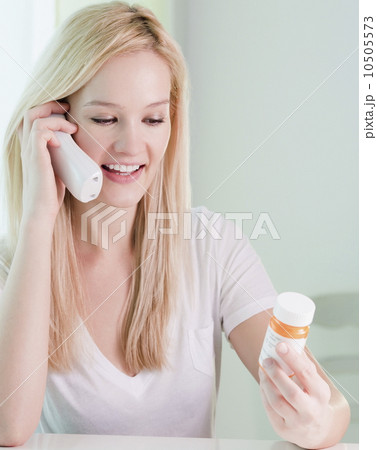 Young woman on phone, holding pill bottle Young woman on phone, holding pill bottle 10505573