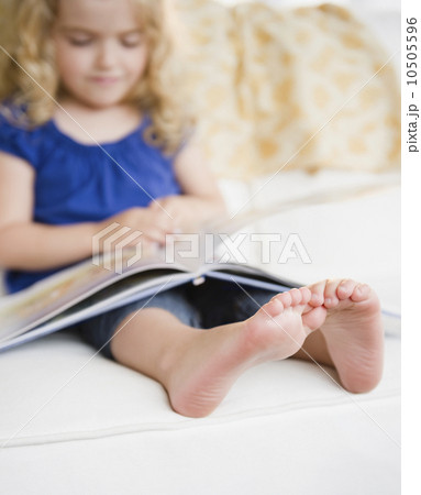 Girl (4-5) reading book 10505596