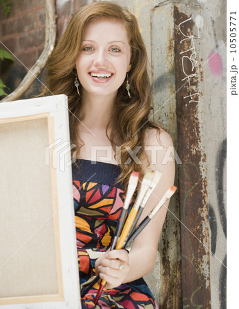Young woman holding paintbrushes and canvas 10505771