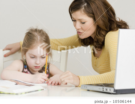 Mother helping daughter with homework 10506144