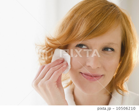 Young woman cleaning face with cotton pad Young woman cleaning face with cotton pad 10506210