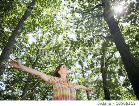 Woman standing below trees with arms outstretched 10506215