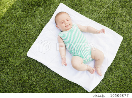 Baby girl (2-5 months) lying on blanket on grass 10506377